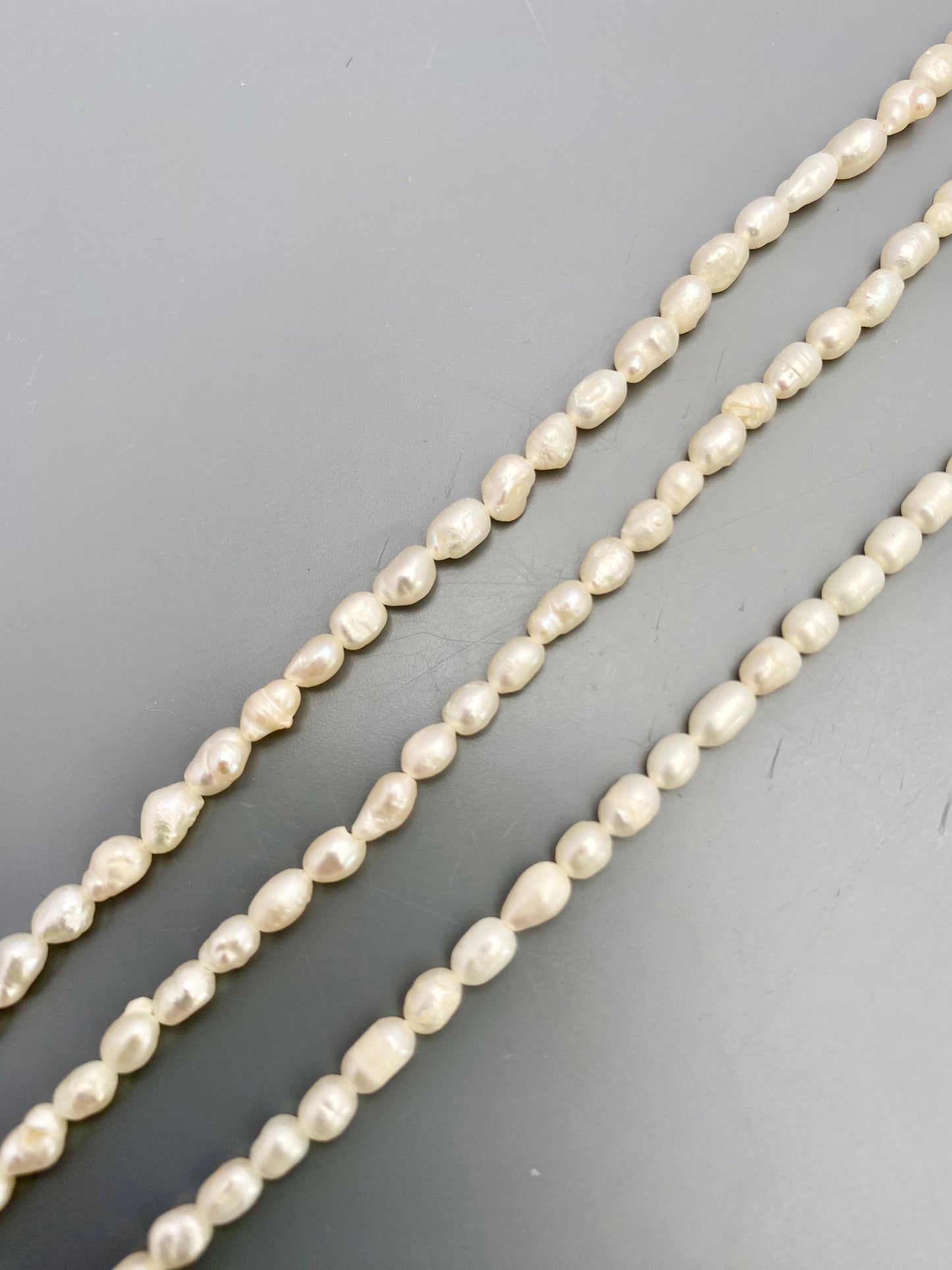 Freshwater rice pearls arranged in a cascading pattern, highlighting their unique textures.