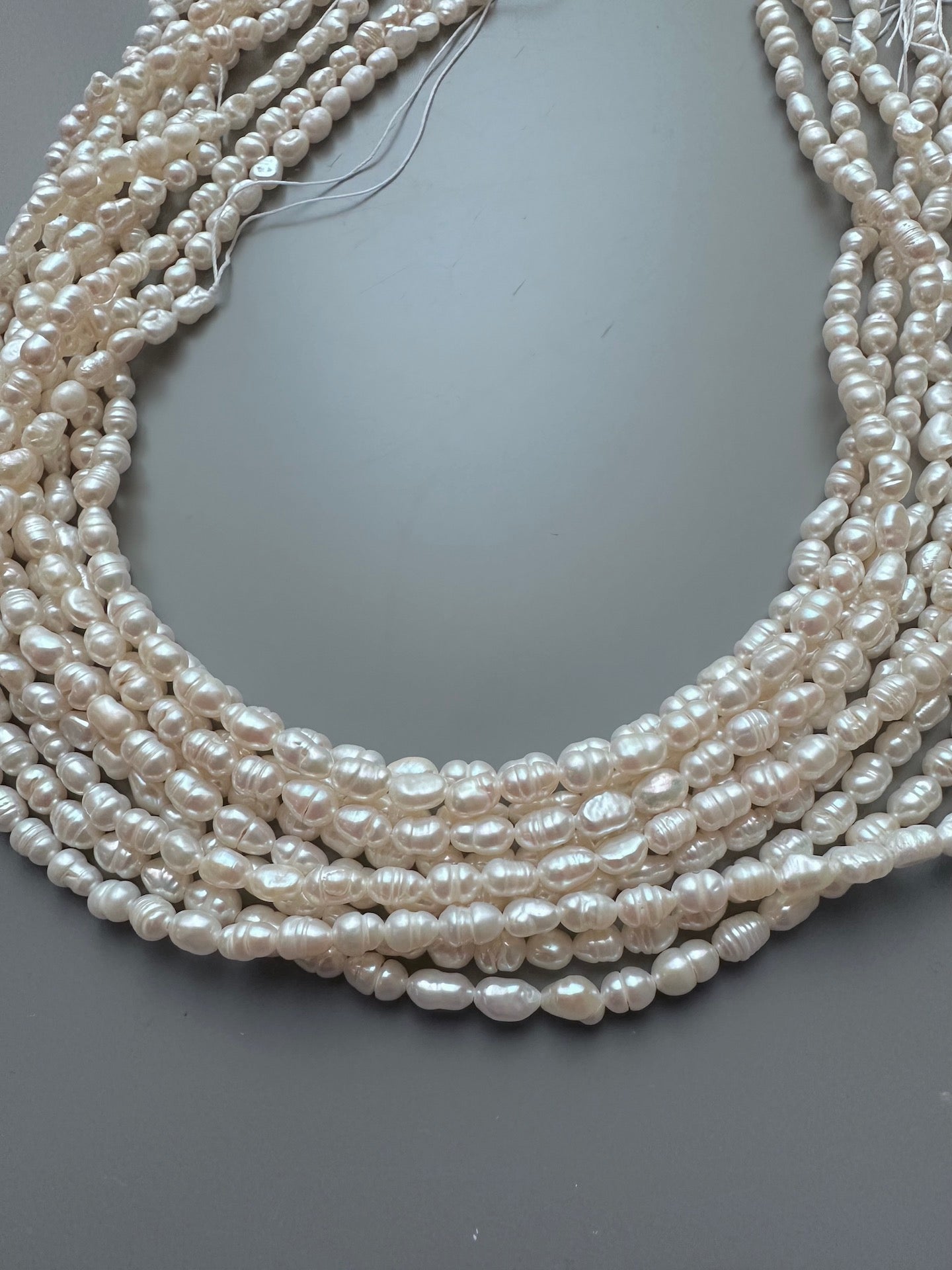 A multi-strand necklace featuring delicate 3.5-4mm freshwater rice pearls in a lustrous white hue.