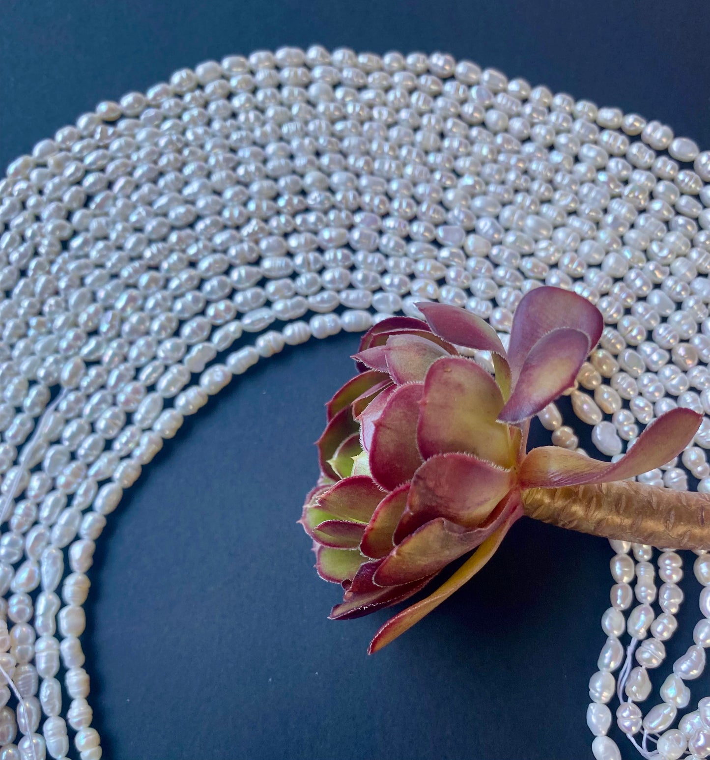 A flower adorns a necklace of 3.5-4mm freshwater rice pearls, blending floral charm with classic elegance.