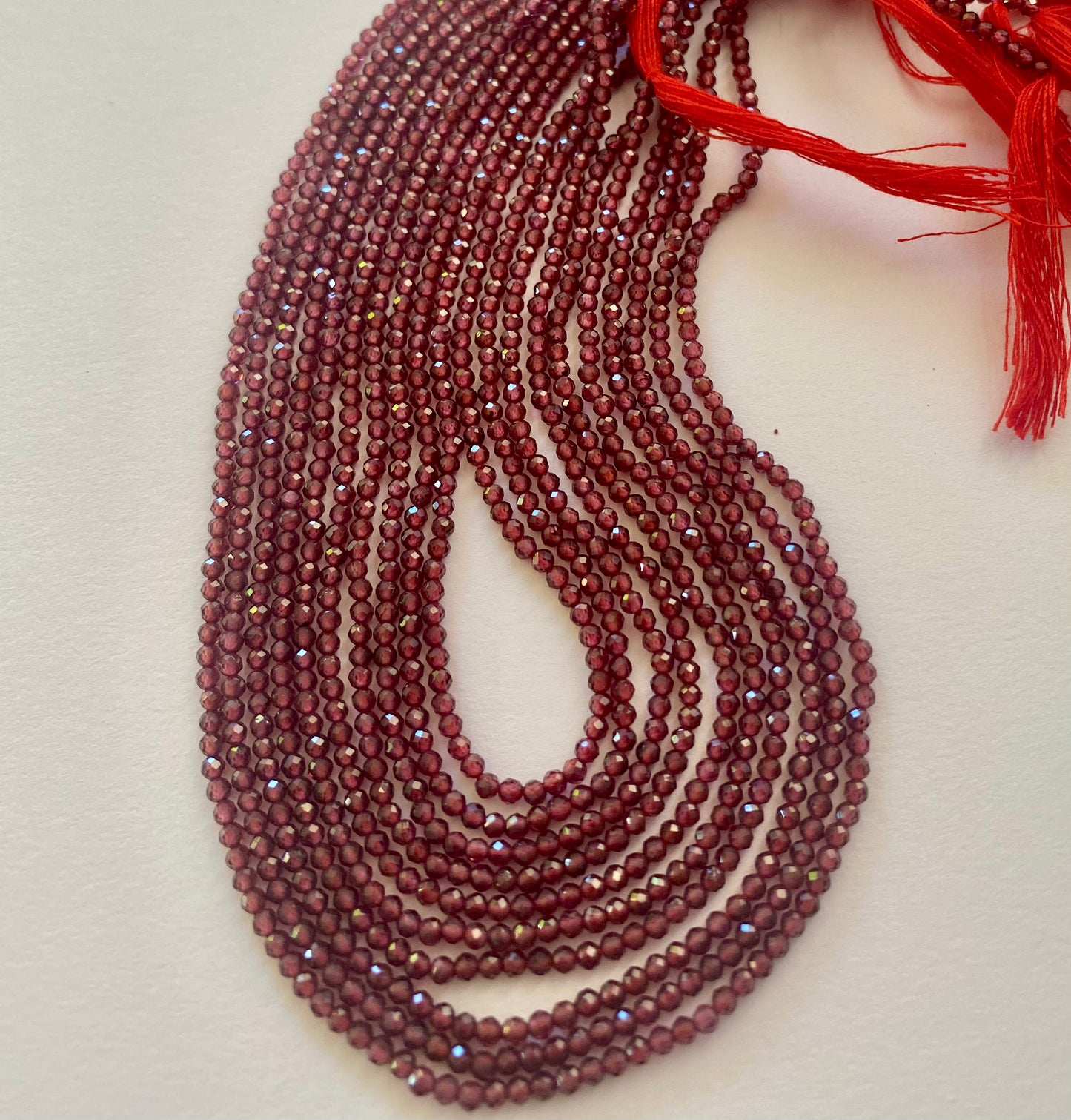 A strand of faceted rondelle garnet gemstone beads, measuring 2.2mm showcasing their vibrant colour and shine.