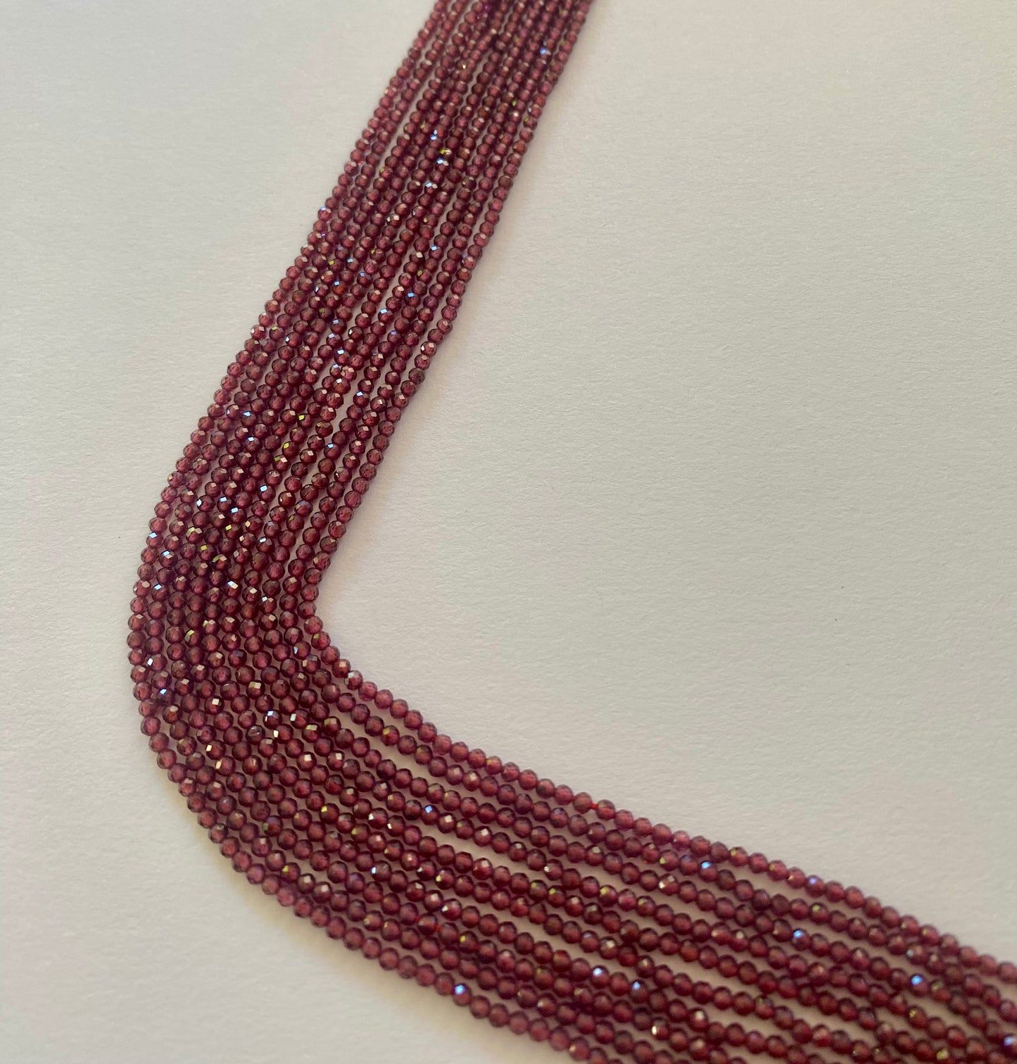 Elegant gemstone strands adorned with 2.2mm smooth red Garnet beads, highlighting their beauty.