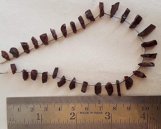 A ruler beside a cluster of garent gemstone beads,.