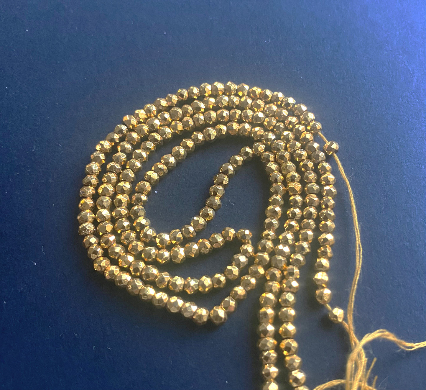 A close-up of Gold Pyrite beads showcasing intricate faceting and polished edges.
