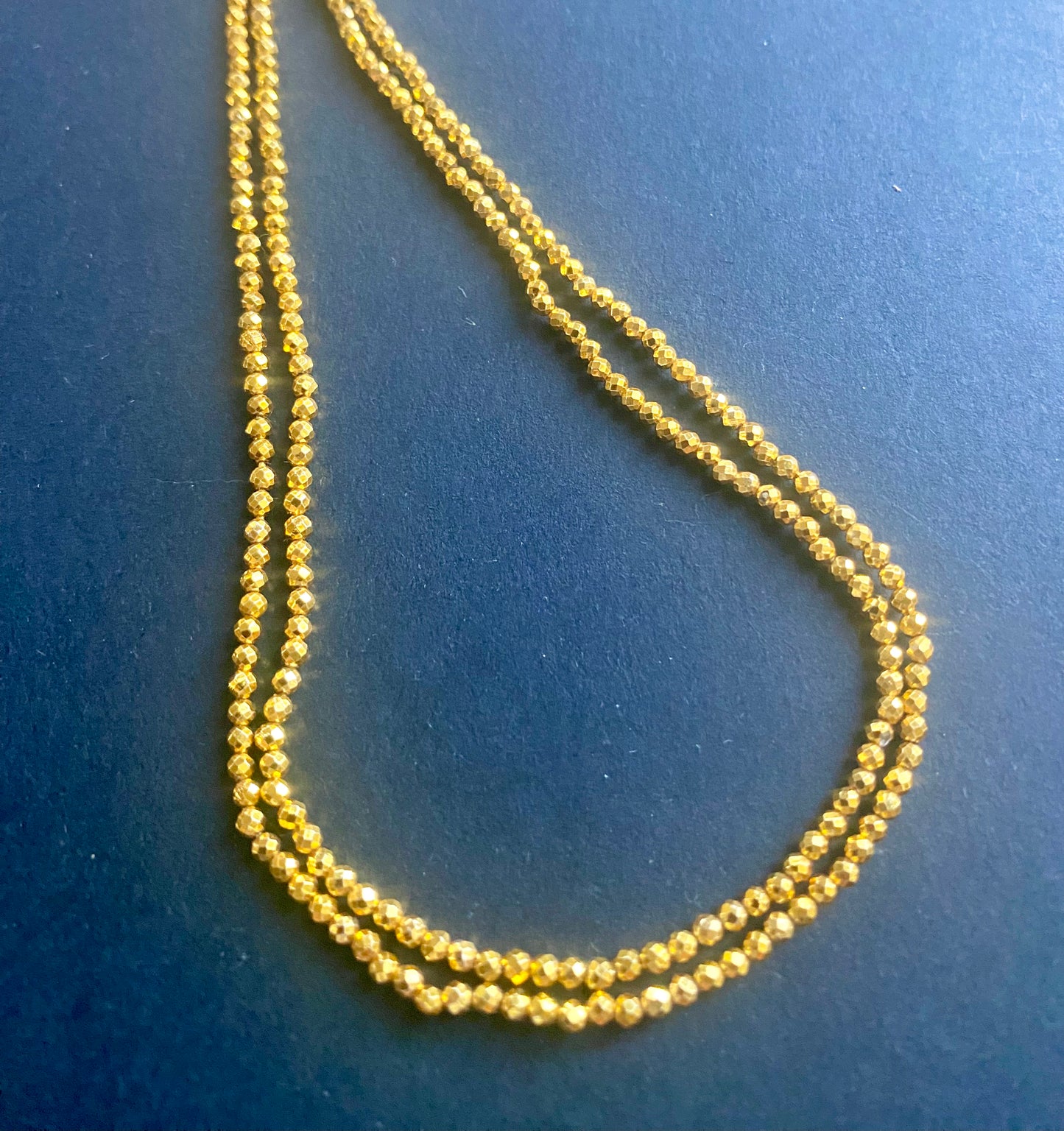 A close-up of a multiple strands featuring gold pyrite faceted rondelle beads, measuring 3-5mm in size.