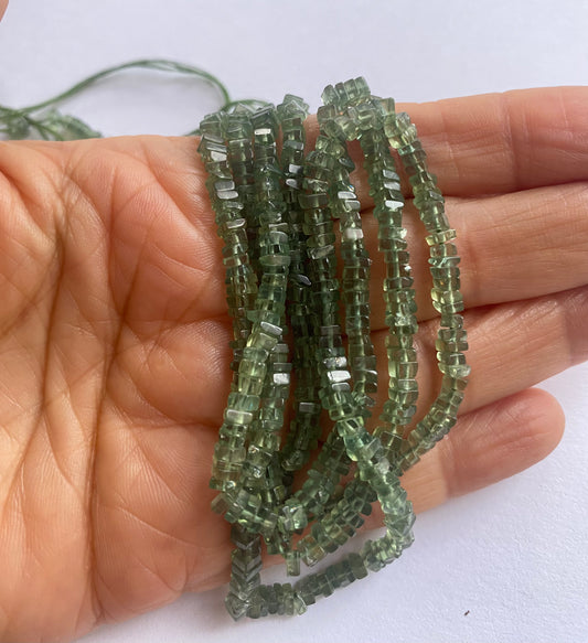 A person holding a apatite gemstone strand, showcasing its green facets and elegant design.