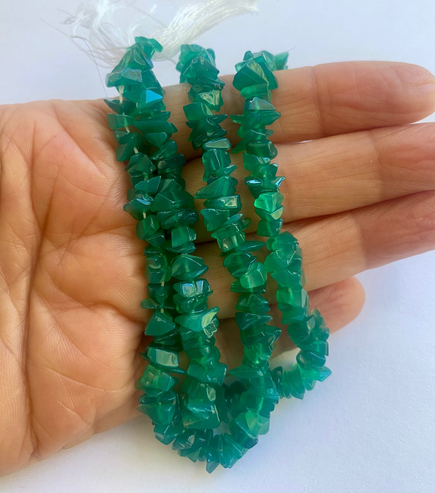 Strand of Uncut Green Onyx beads arranged neatly for artisan beading projects.