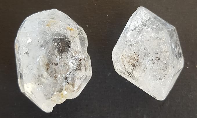Two undrilled clear Herkimer Diamond, elegantly positioned on a dark black surface