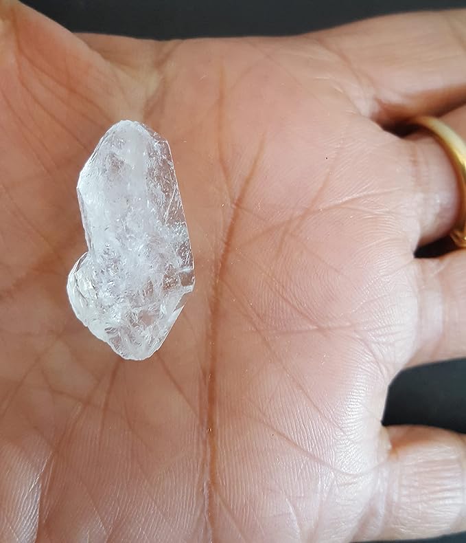 A person holding a rough Herkimer diamond gemstone showcasing the colour and shape.
