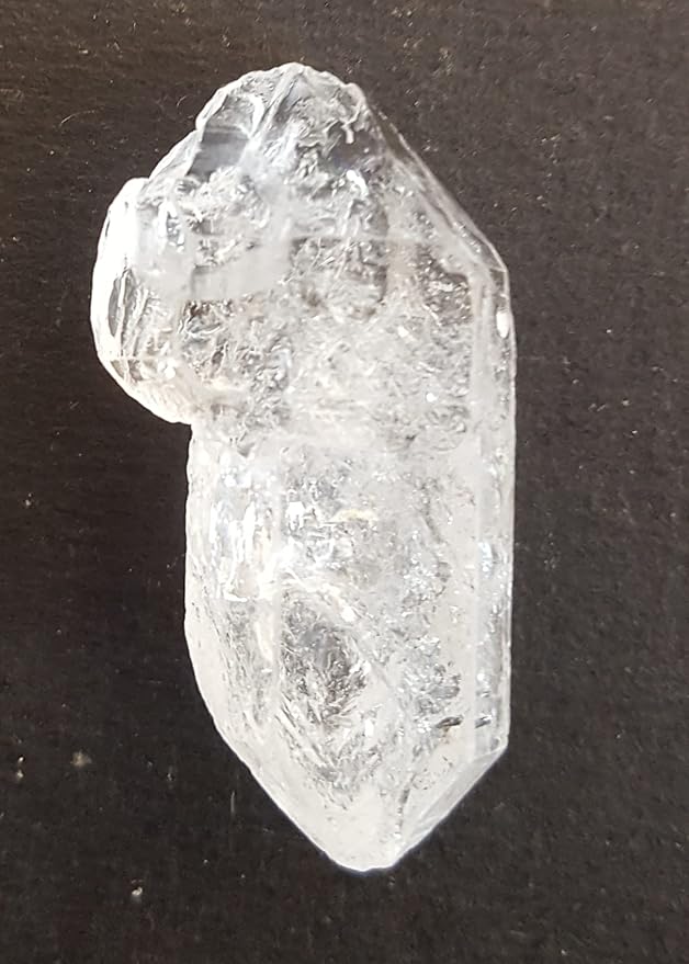 A rough Herkimer diamond gemstone displayed on a table, highlighting its unique shape and brilliant clarity.