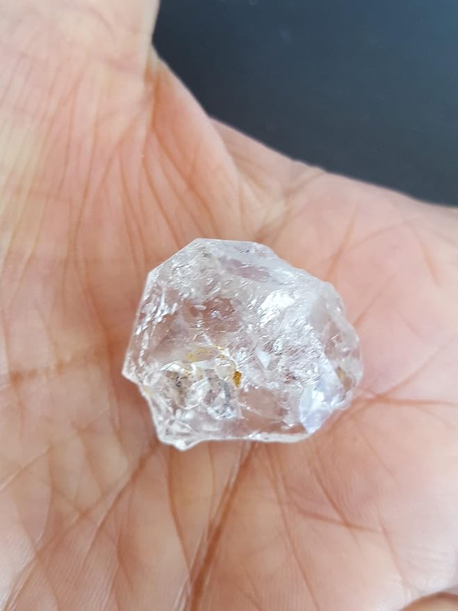 A person holding a undrilled herkimer diamond beads, showcasing the colour and shape.
