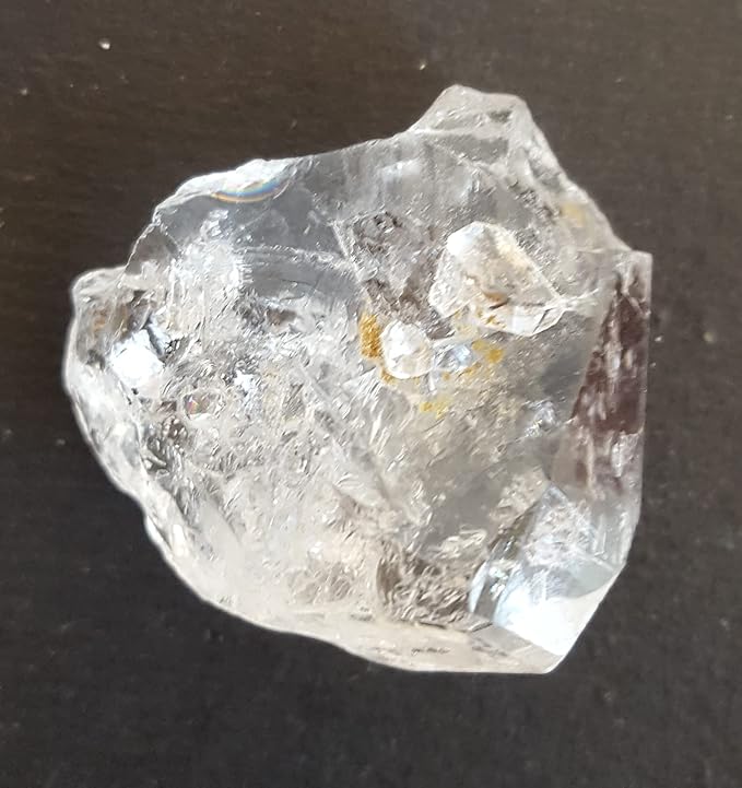 A rough Herkimer diamond gemstone displayed on a table, highlighting its unique shape and brilliant clarity.