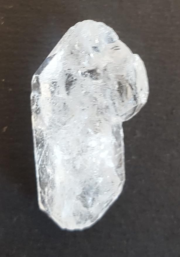 A Herkimer diamond stone bead on a table, featuring its unpolished surface and striking clarity, capturing light beautifully.