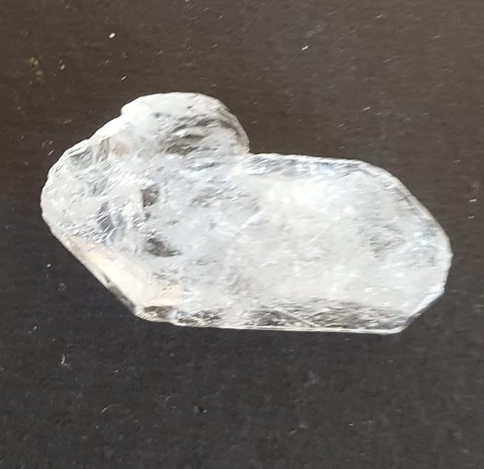 A rough Herkimer diamond gemstone bead displayed on a table.