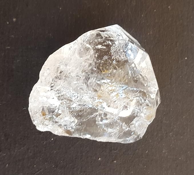 A Herkimer diamond gemstone resting on a table, showcasing its natural rough texture and sparkling facets.