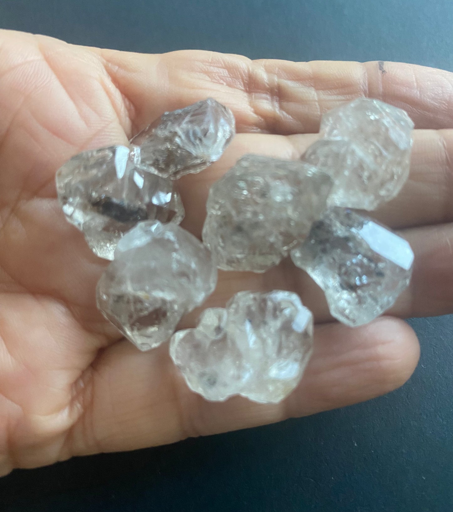 A person holding herkimer beads, measuring 14-16mm in size.
