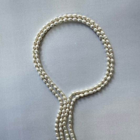 Natural freshwater pearl beads glistening under light, showcasing their refined elegance and smooth surface.