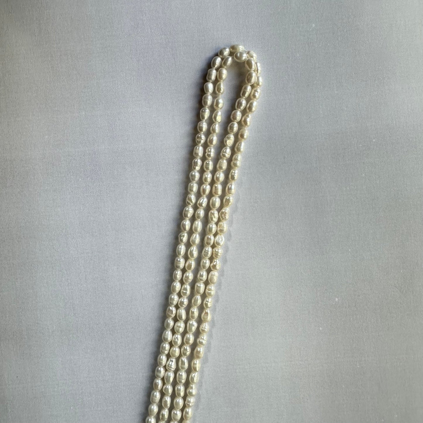 Loose freshwater pearl smooth rice beads spread out, revealing their consistent sizing and high-quality craftsmanship.