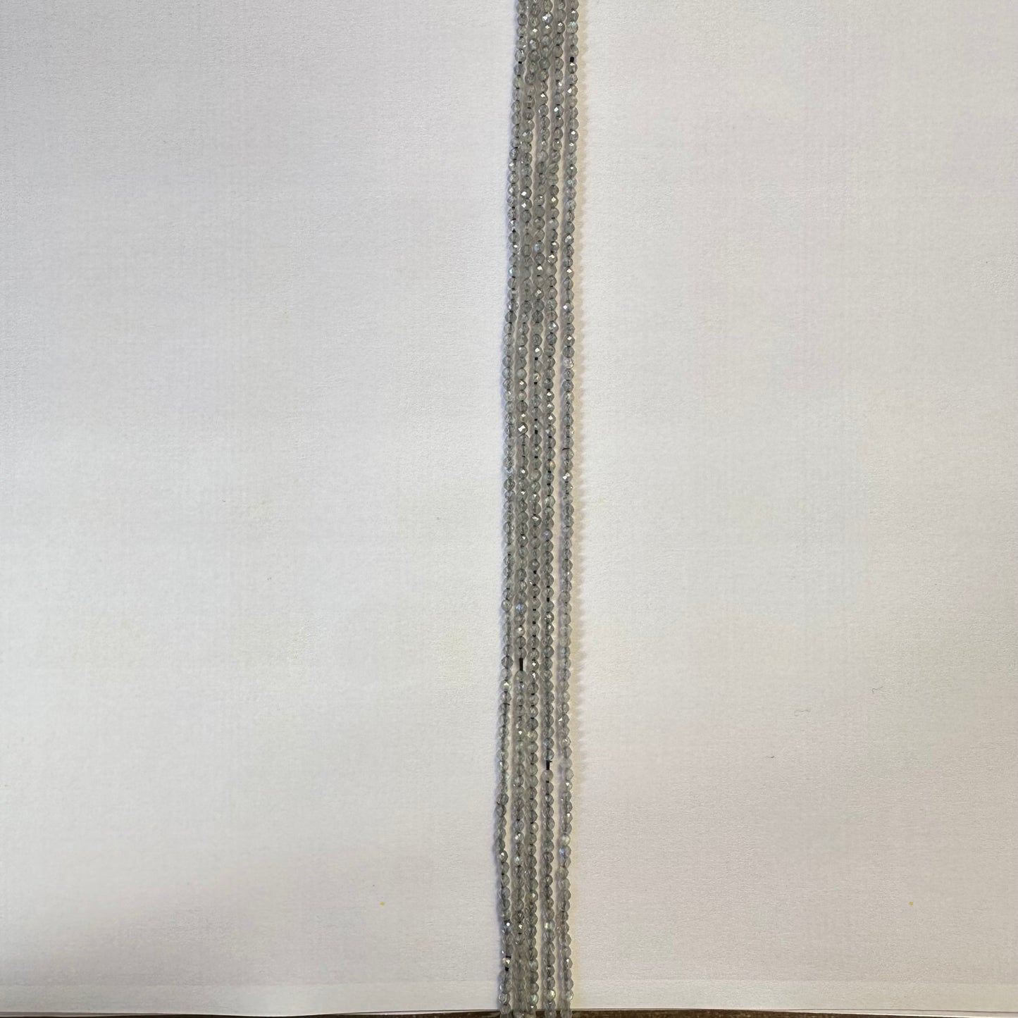 A jewellery artist arranges Labradorite beads, creating a refined gemstone piece with balanced proportions.