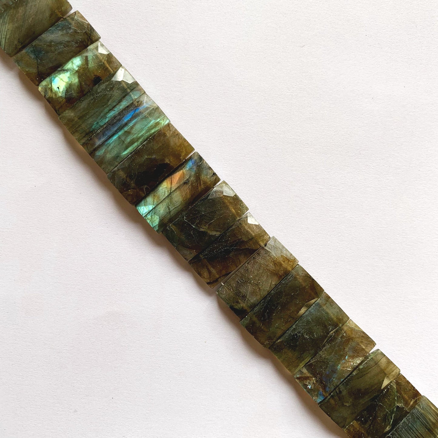 A person holds delicate strands of Labradorite beads, showcasing their smooth design.