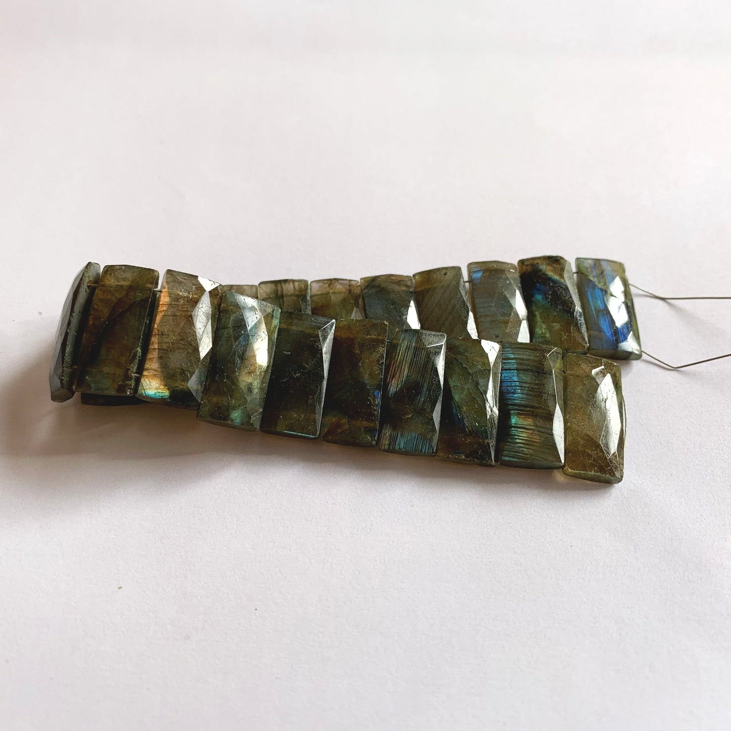A dial gauge measures the Labradorite faceted rectangle 21mm x 9.5–10mm gemstone.