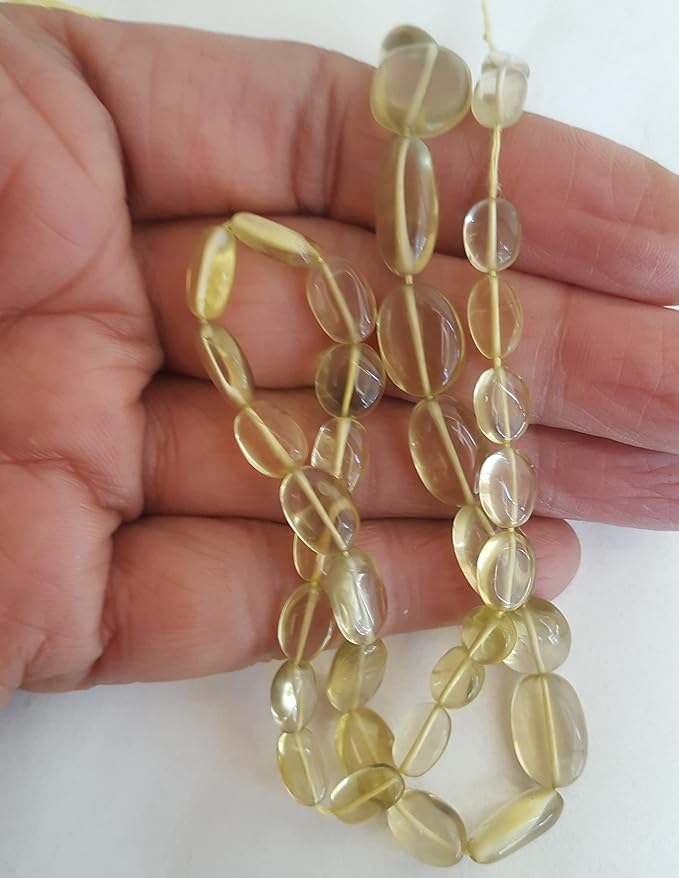 A person holding a smooth oval lemon quartz gemstone strand, showcasing its yellow smooth and elegant design.