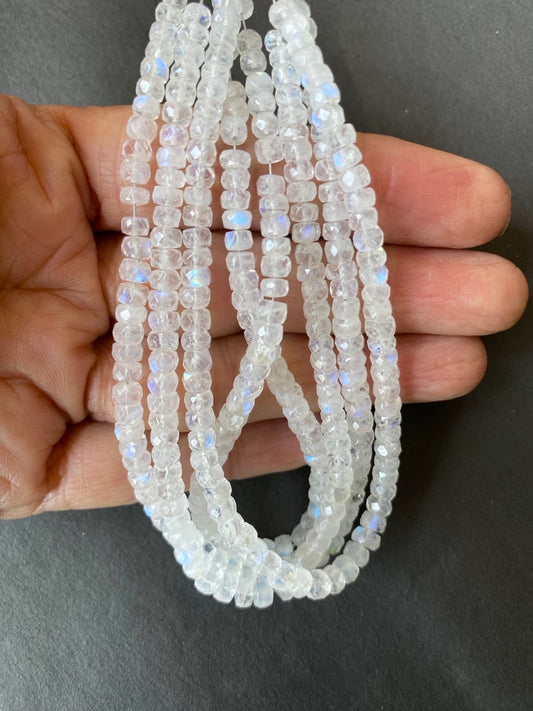 A hand displays a collection of moonstone beads, each measuring 4mm to 5mm in size.