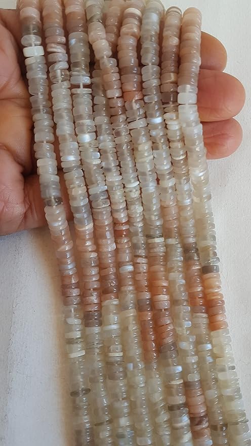 A hand holds stunning strands made of smooth wheel moonstone gemstones.