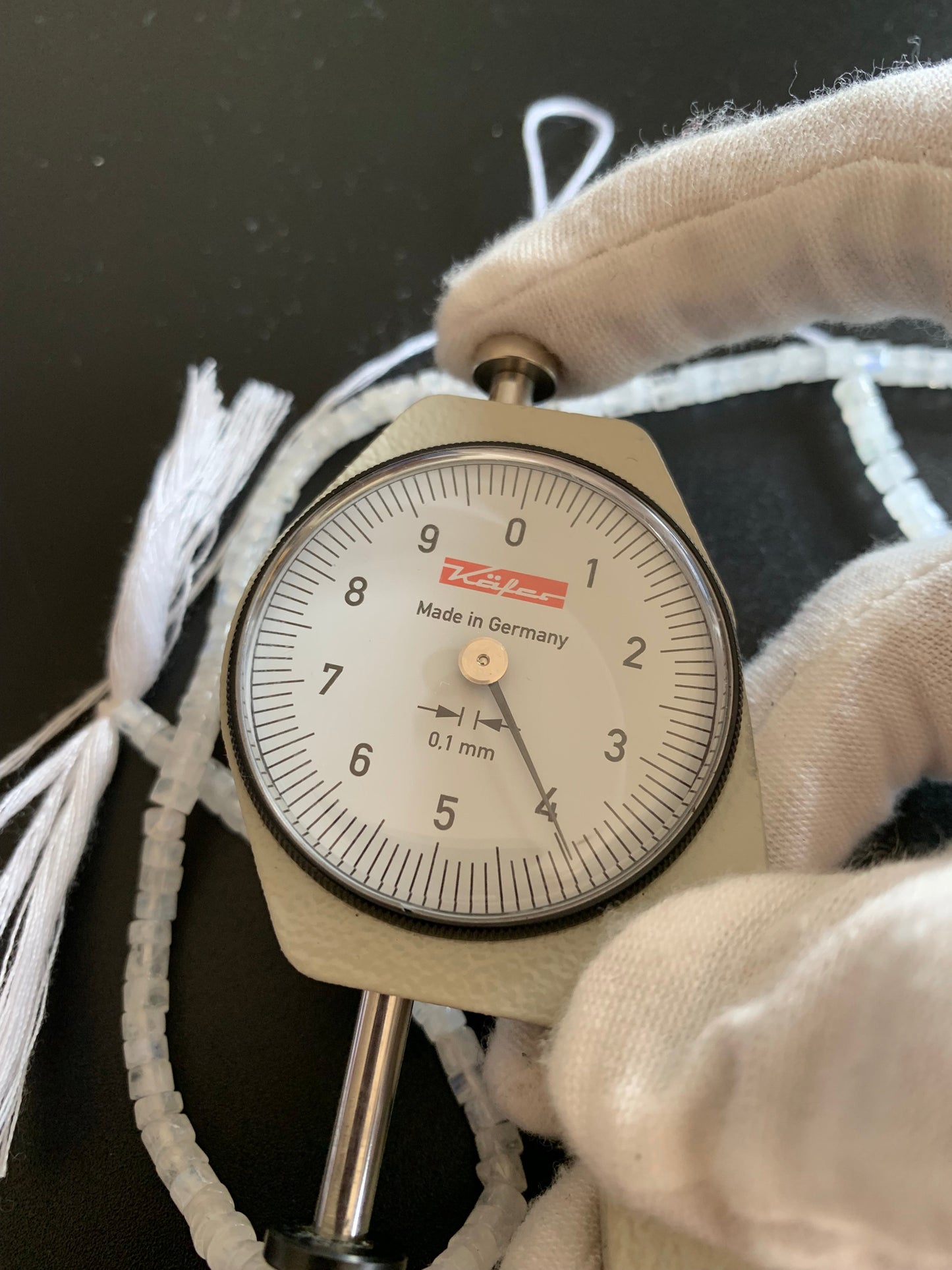 A dial gauge measures the Moonstone smooth wheel 3.8-4mm gemstone.