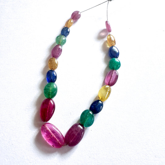 Close-up of 45 carats of yellow and blue sapphire, ruby, and emerald beads in smooth oval cut.