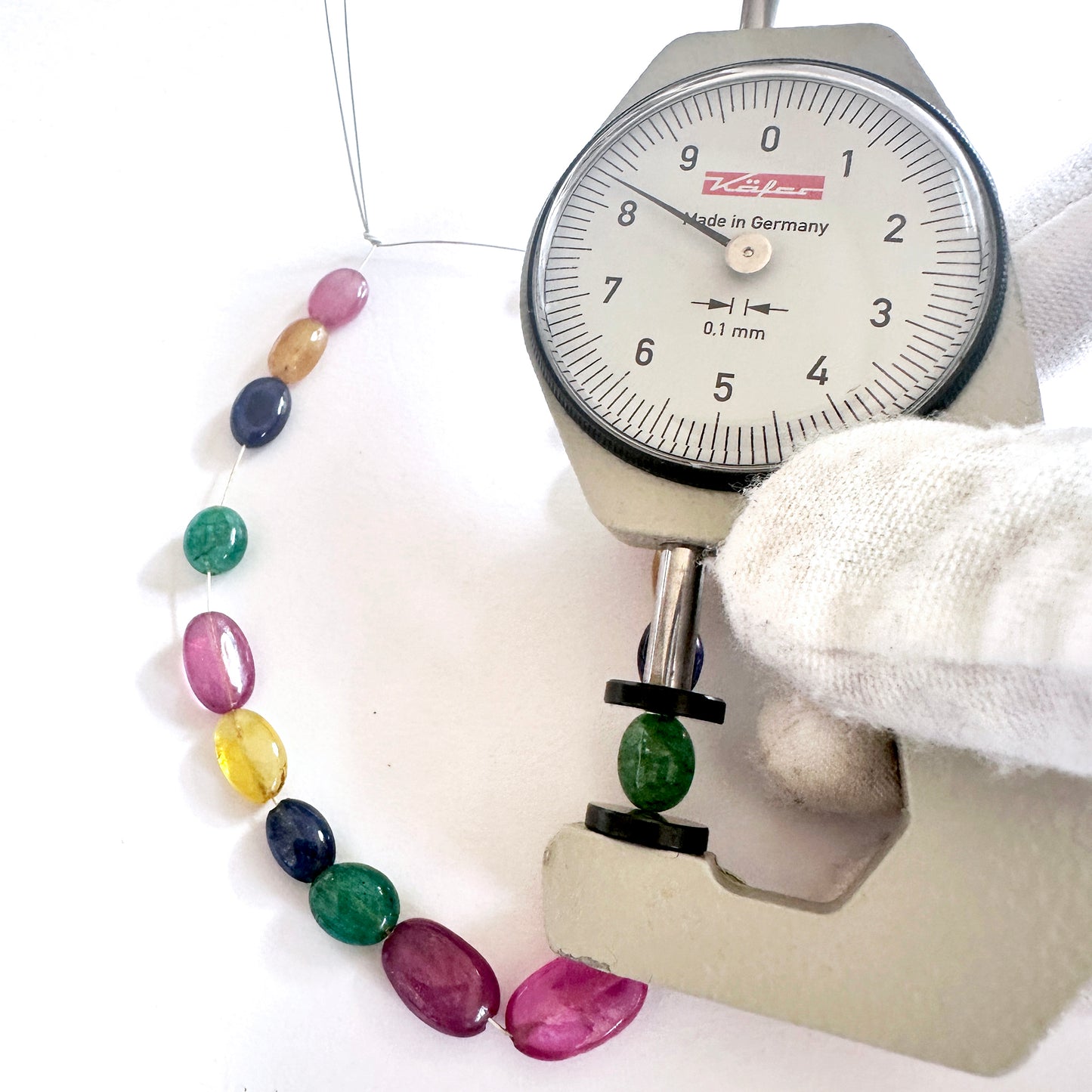 A dial gauge measures the blue sapphire smooth oval gemstone for precision and quality.