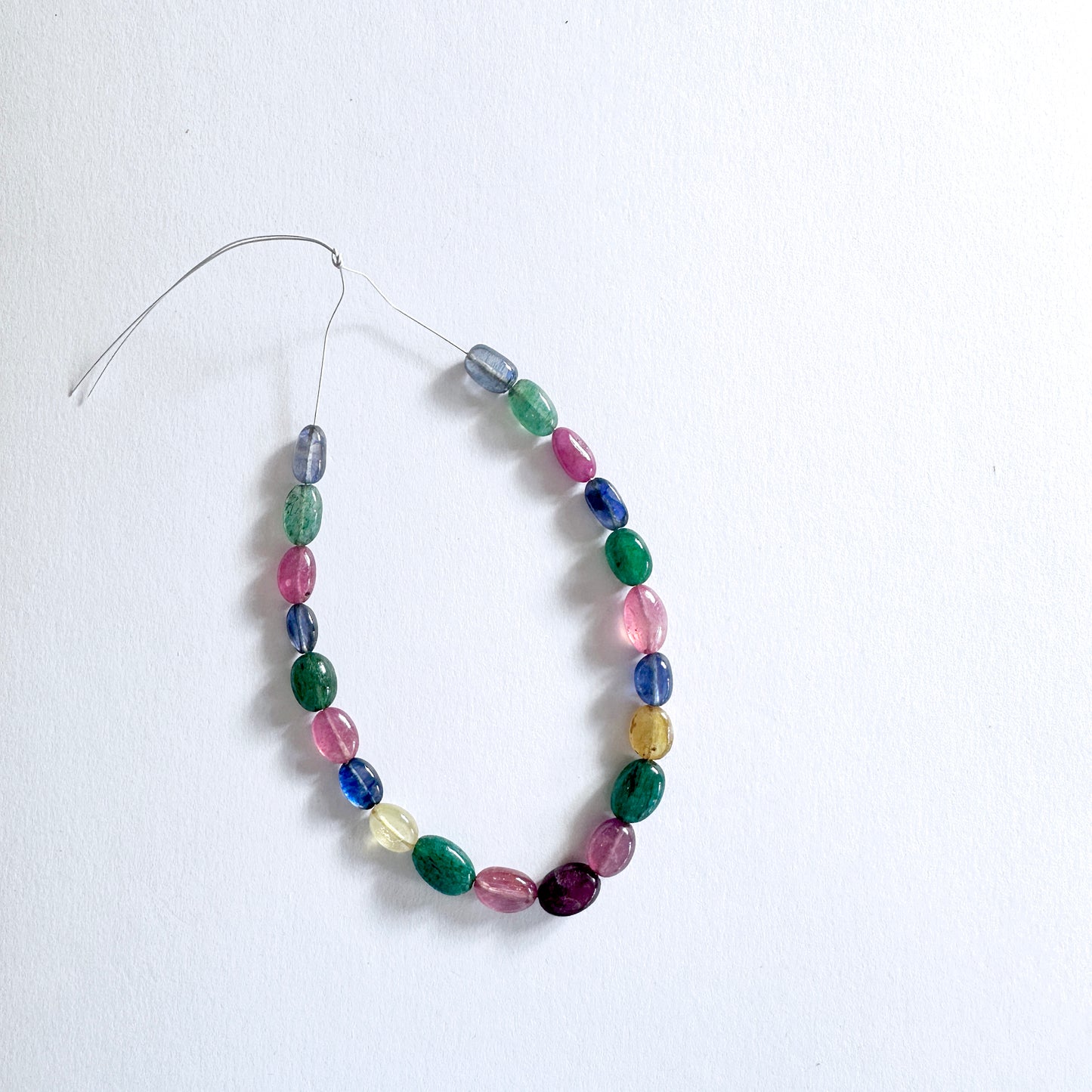 Mixed gemstone beads in oval cut display vivid reds, blues, yellows, and greens with elegant shine.