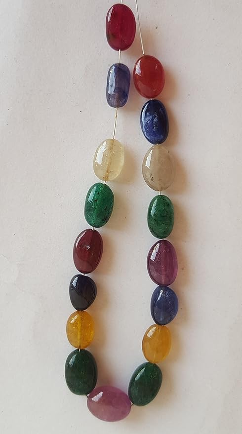 A colourful strand made of smooth oval beads in ruby, blue sapphire, yellow sapphire, and emerald against a white backdrop.