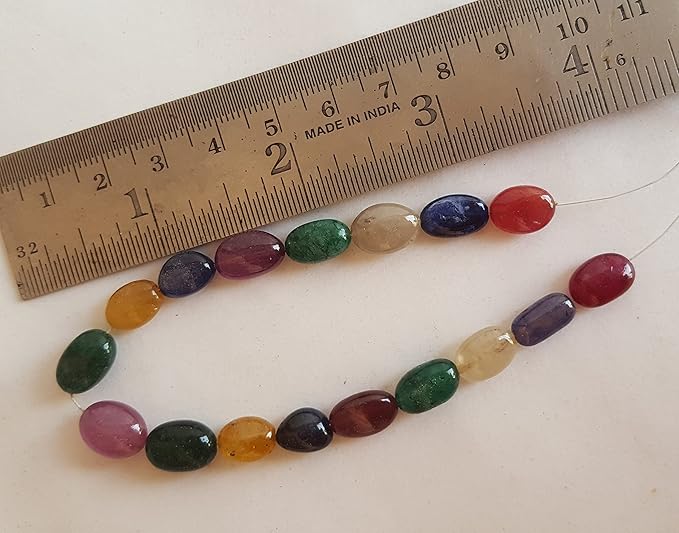 Close-up of a measuring ruler alongside a vibrant collection of precious gemstone beads.