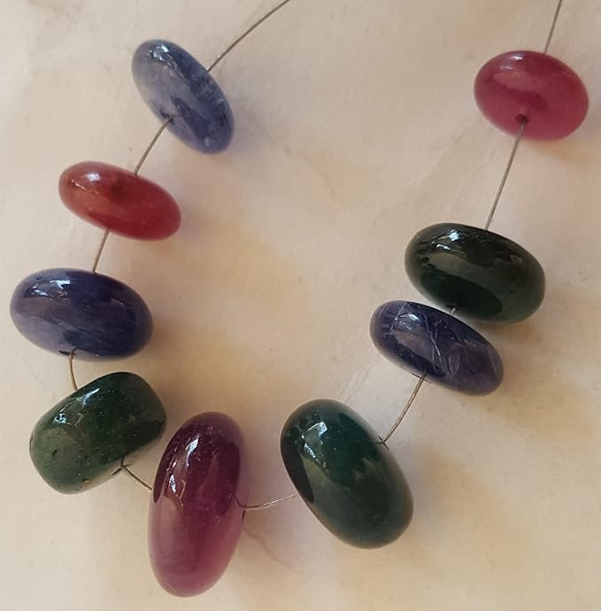 A vibrant multi-coloured strand featuring ruby, blue sapphire, and emerald beads on a white background.
