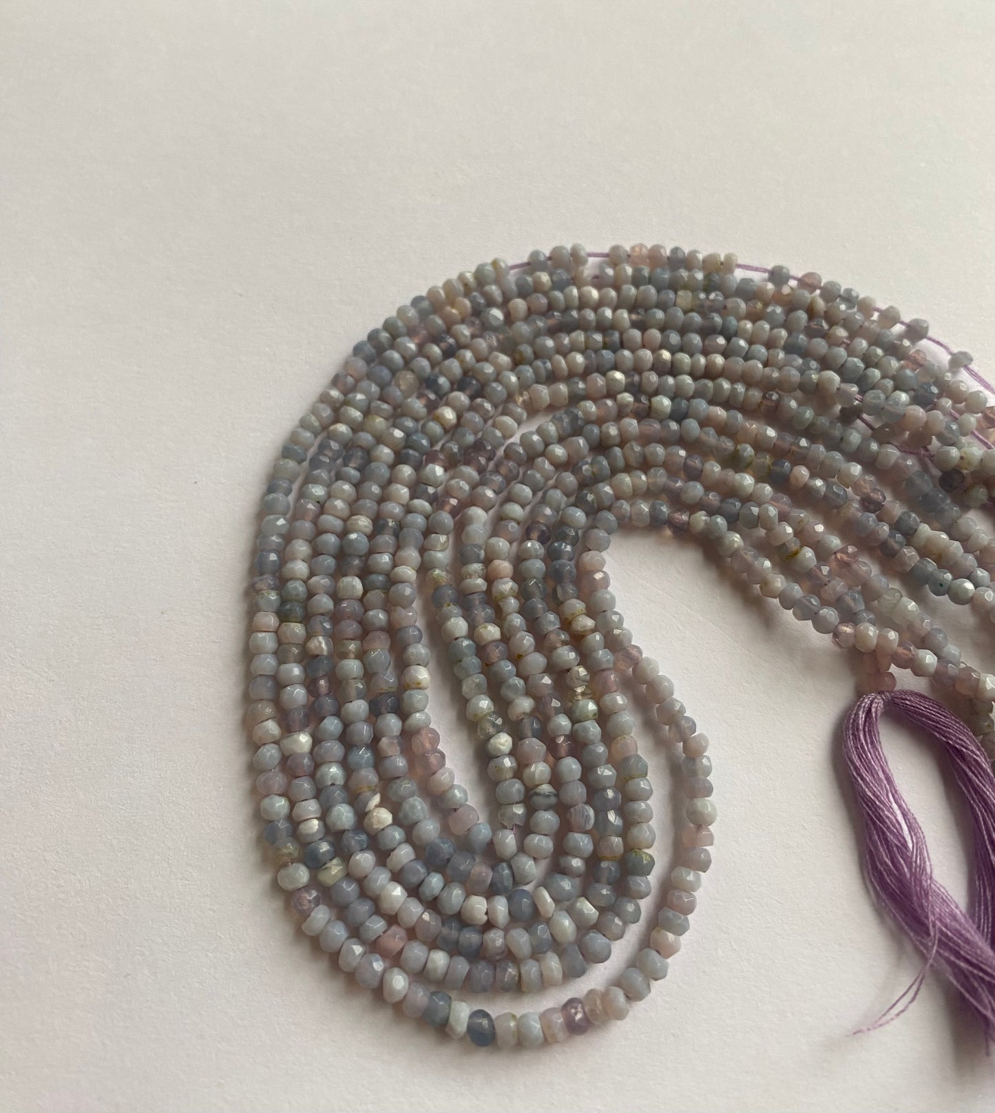 Strand of Faceted Rondelle Lavender Opal beads arranged neatly for artisan beading projects.