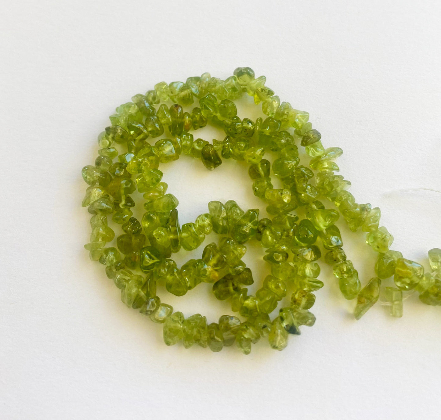Vibrant Peridot chip beads 5 to 8mm with a polished finish arranged in a 45cm strand for jewellery making.