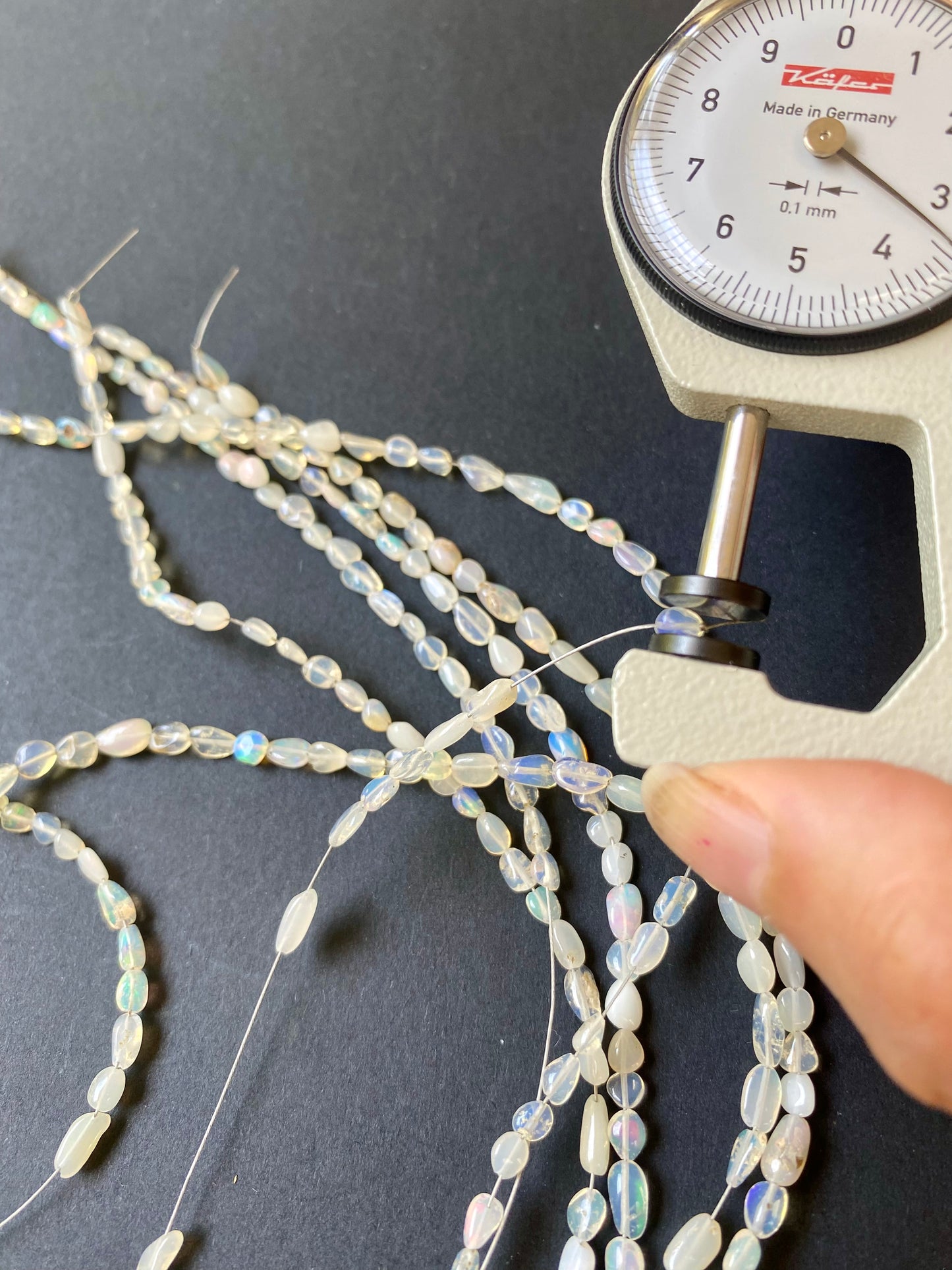 Detailed view of a measuring dial gauge and gemstone bead, emphasising the dimensions for crafting Opal gemstone beads.