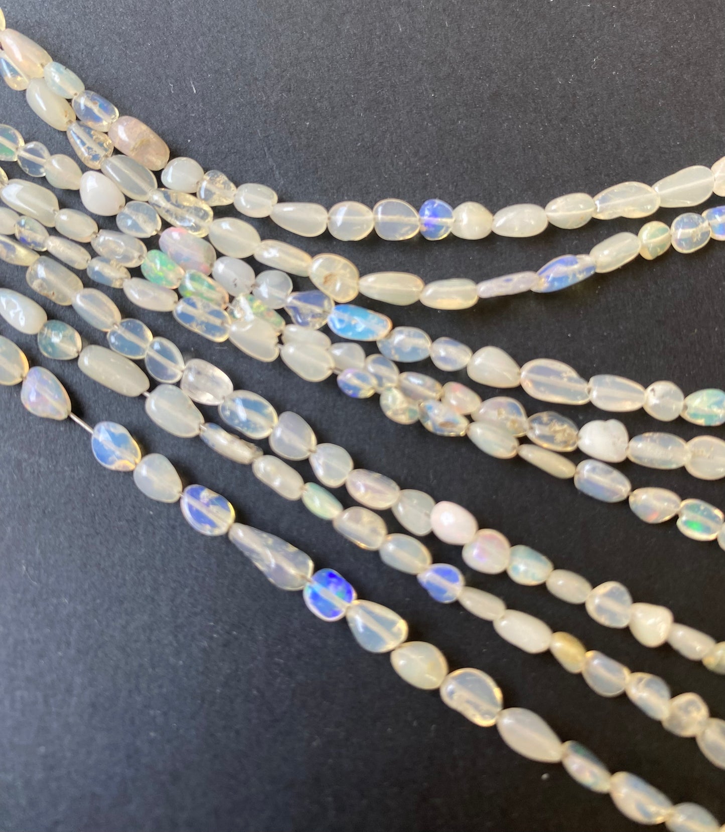 Stunning smooth tumble white opal gemstone beads, reflecting the unique charm of the opal semi-precious gemstone.