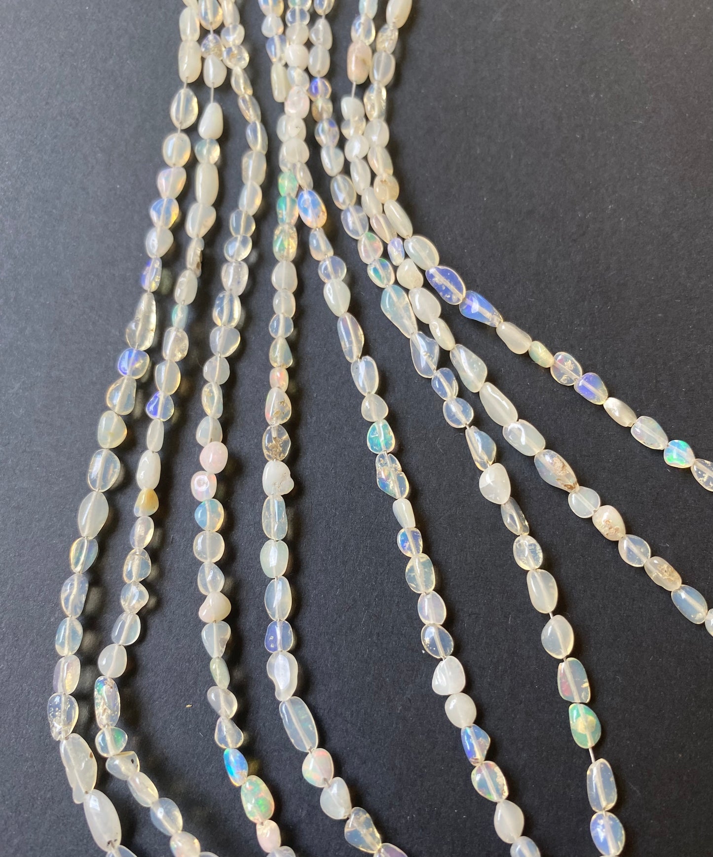Elegant gemstone strand adorned with smooth tumble white opal beads, highlighting the beauty of the opal gemstone beads.