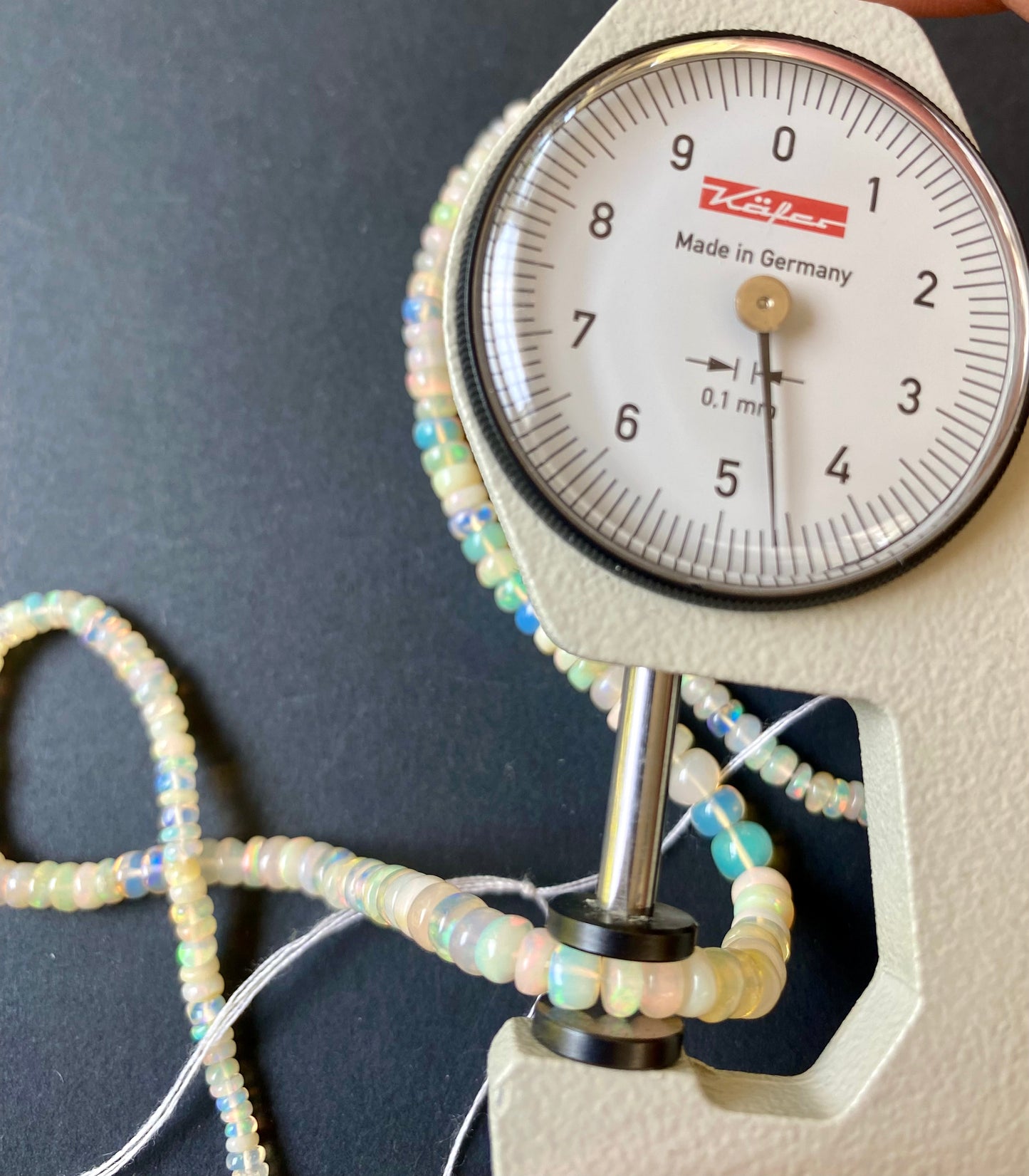 Detailed view of a measuring dial gauge and gemstone bead, emphasising the dimensions for crafting Opal gemstone beads.