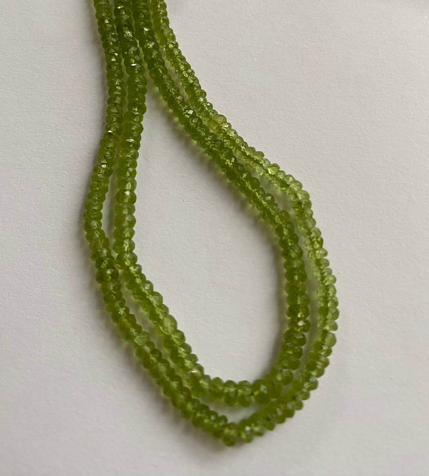 Strand featuring faceted rondelle peridot gemstones, ranging from 3.7mm to 4.4mm, in a stunning green hue.