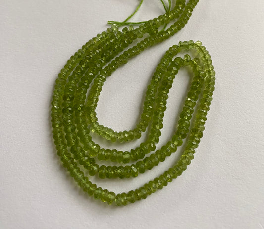 A strand of faceted green peridot rondelle gemstone beads, measuring 3.7mm to 4.4mm, showcasing their vibrant colour and shine.