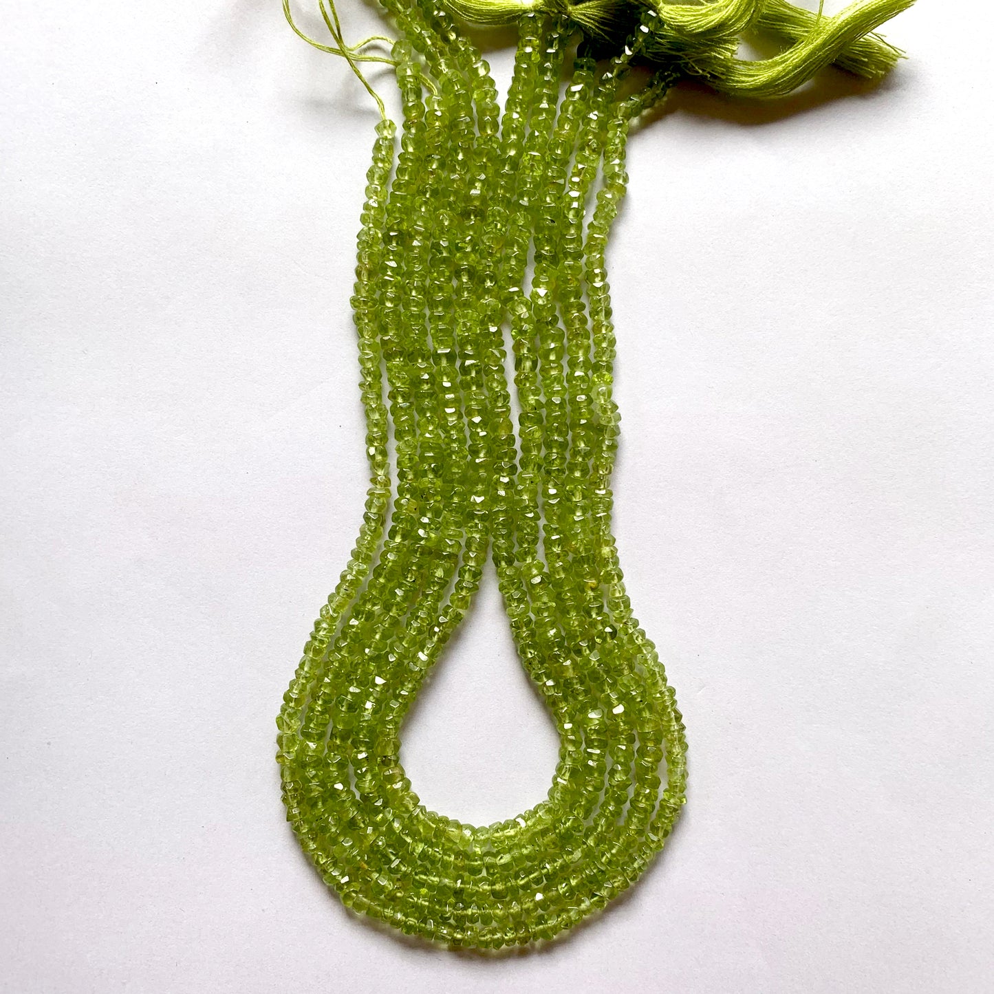 Strand featuring faceted rondelle peridot gemstones, ranging from 3.7mm to 4.4mm, in a stunning green hue.