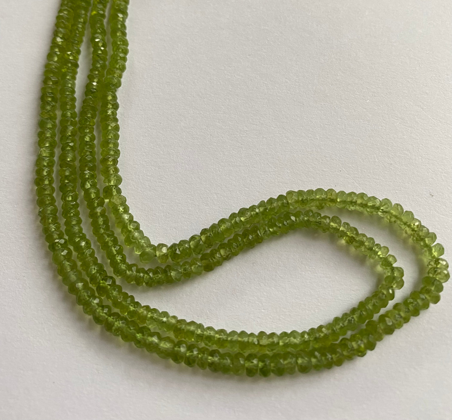 Beautiful strands of precious green peridot gemstone beads, featuring faceted rondelles sized between 3.7mm and 4.4mm, radiating elegance.