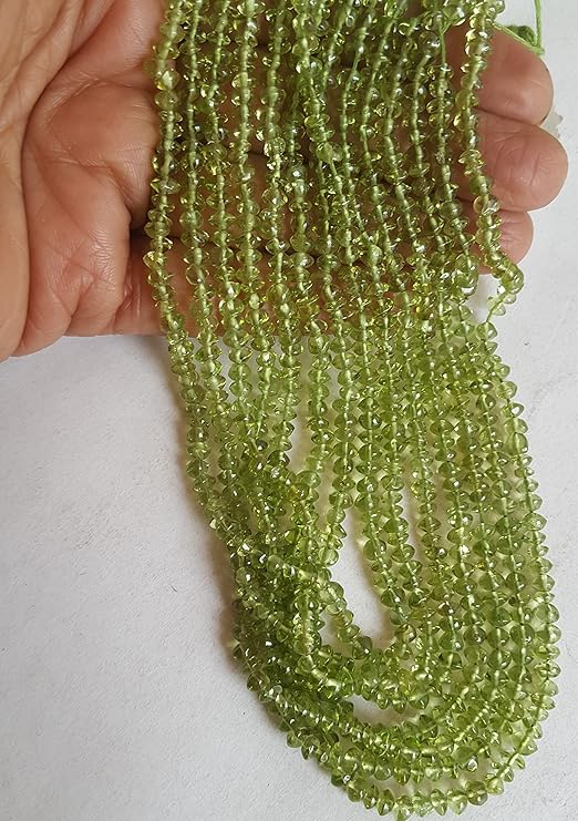 A close-up of strands of green Peridot beads, 3.5mm to 4mm in size, highlighting their faceted rondelle design and rich hue.