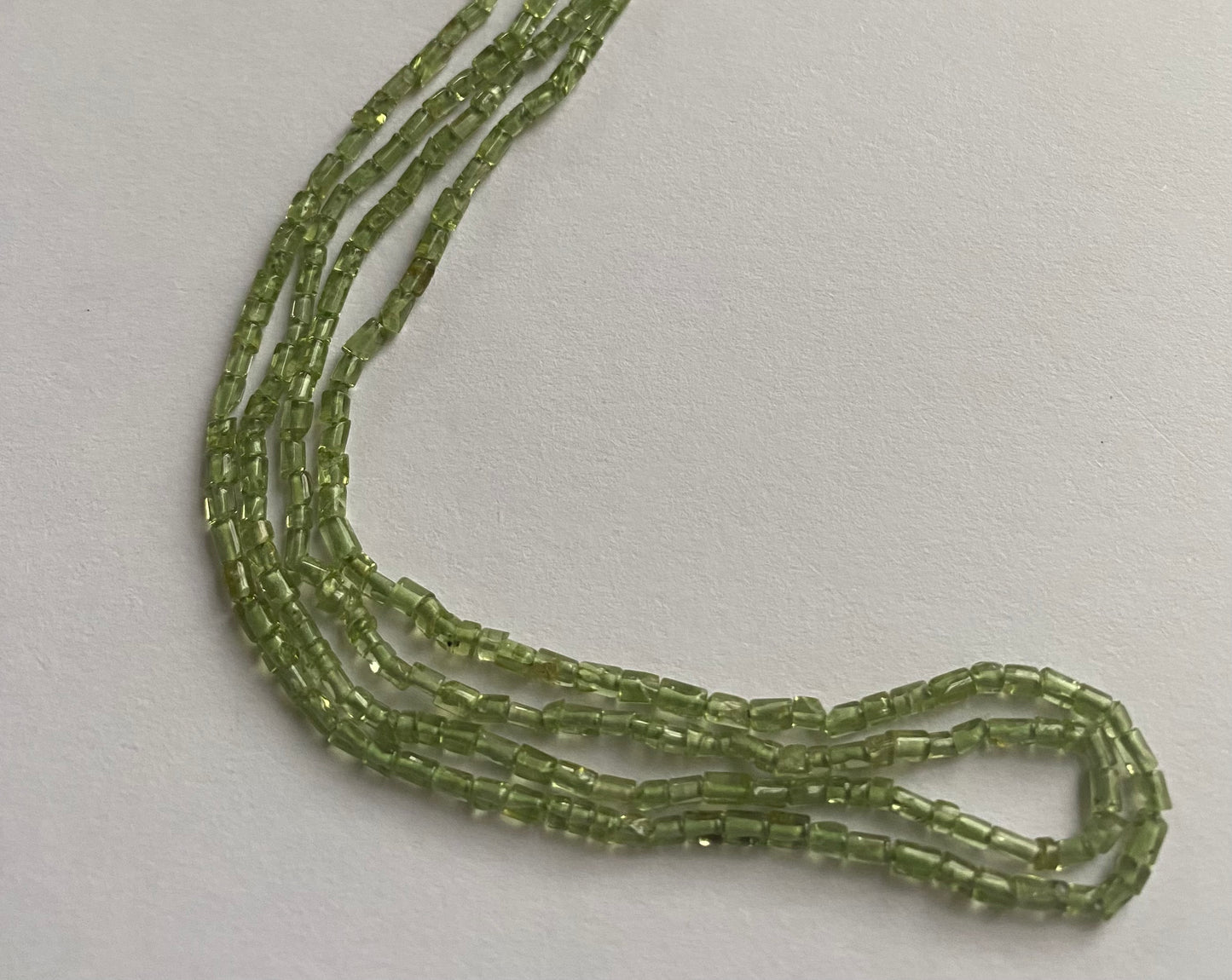 Strand featuring peridot tube shaped gemstones, ranging from 2mm to 2.2mm, in a stunning green hue.