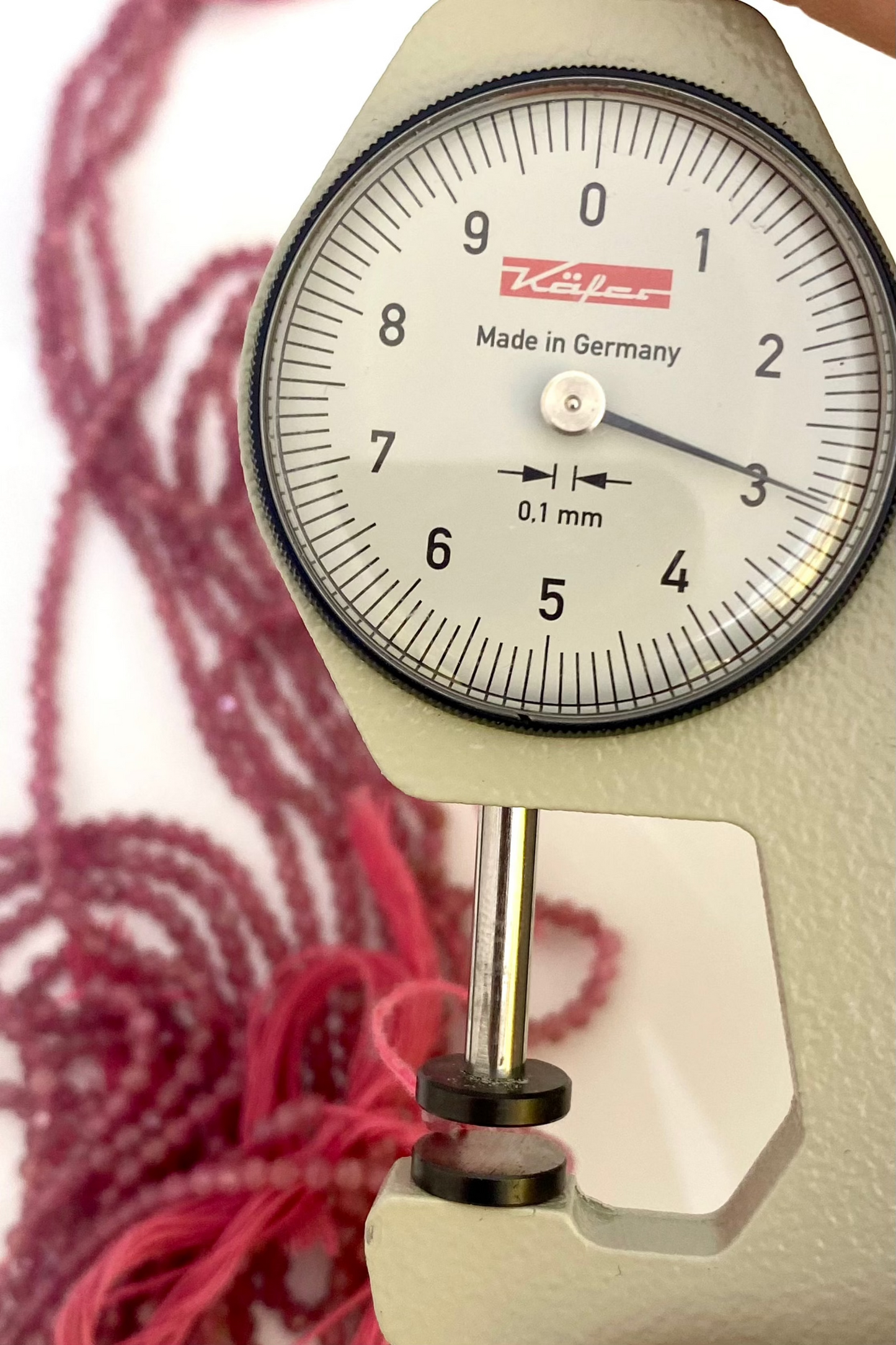 Close-up of a gauge displaying red beads, featuring 3mm faceted rondelle pink tourmaline beads.