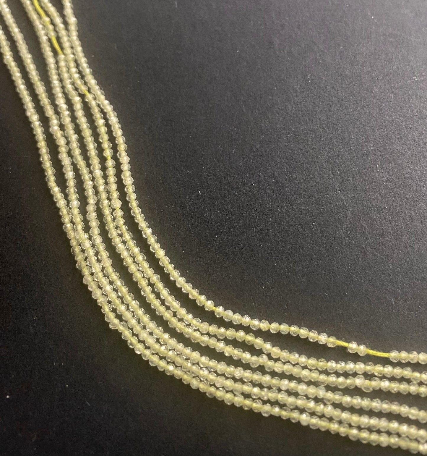 A vibrant assortment of faceted Prehnite gemstone beads, measuring 1.9mm, arranged in a group.