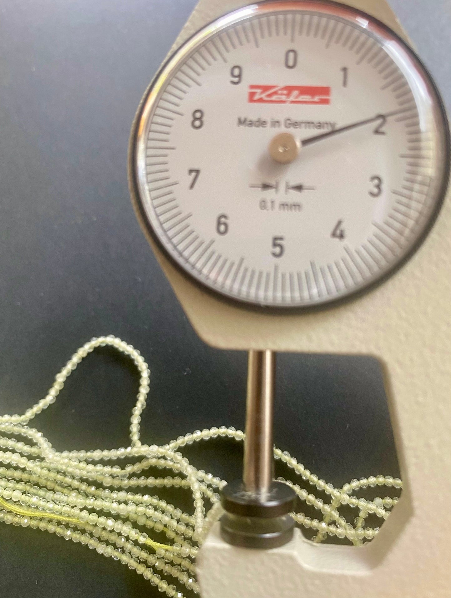 A dial gauge measures the Green Amethyst Faceted Rondelle 2.2mm gemstone.
