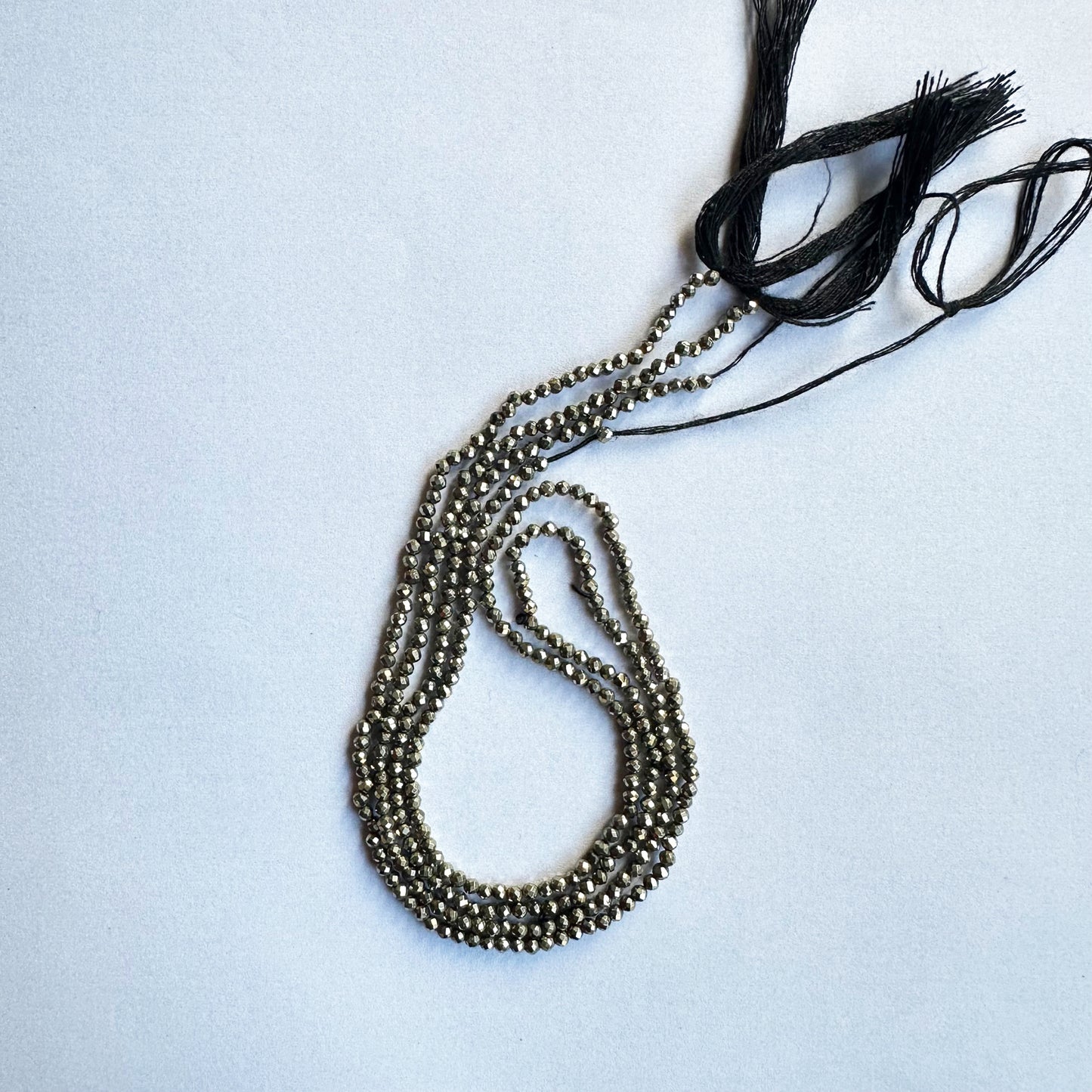 Pyrite rondelle beads sparkle under soft lighting, enhancing their elegant faceted finish.